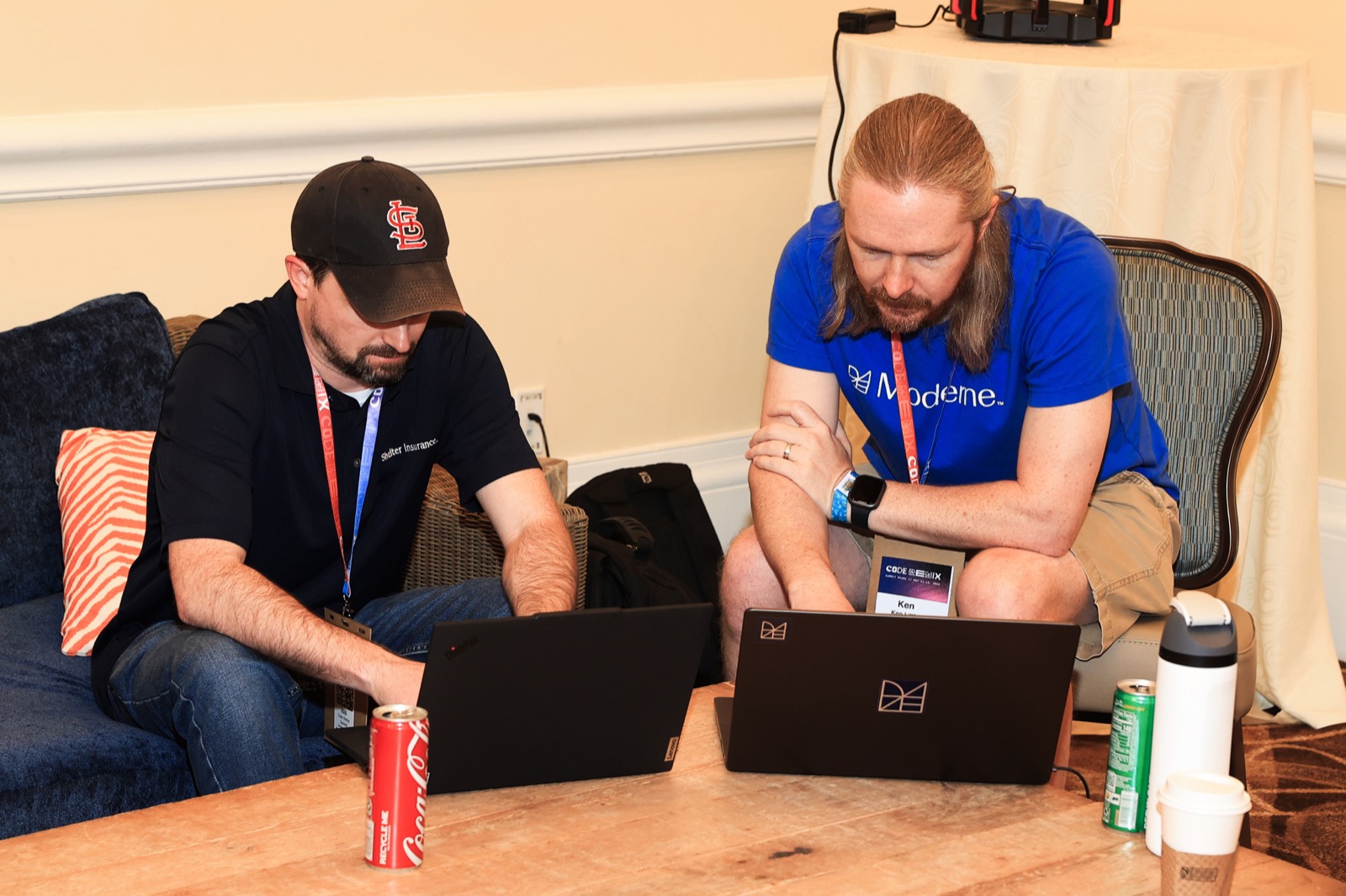 Two attendees working on laptops at a CodeRemix summit lounge